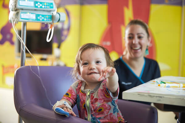 A little patient at Centenary Hospital for Women and Children A smiling baby with an IV line reaches for the camera