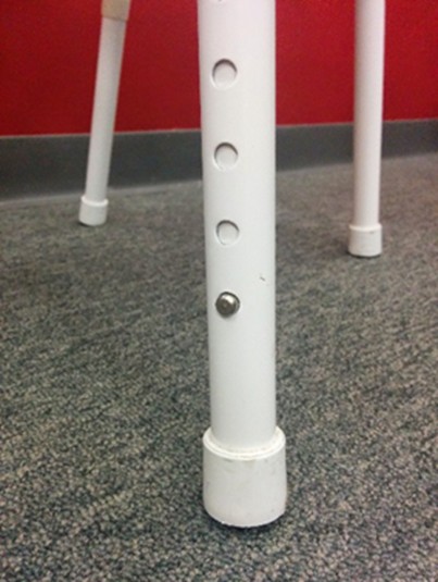 Close-up of adjustable shower stool leg with push button