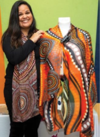Person standing beside and holding a brightly patterned shawl displayed on a mannequin
