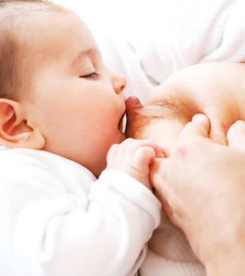 Baby lining mouth with nipple holding finger