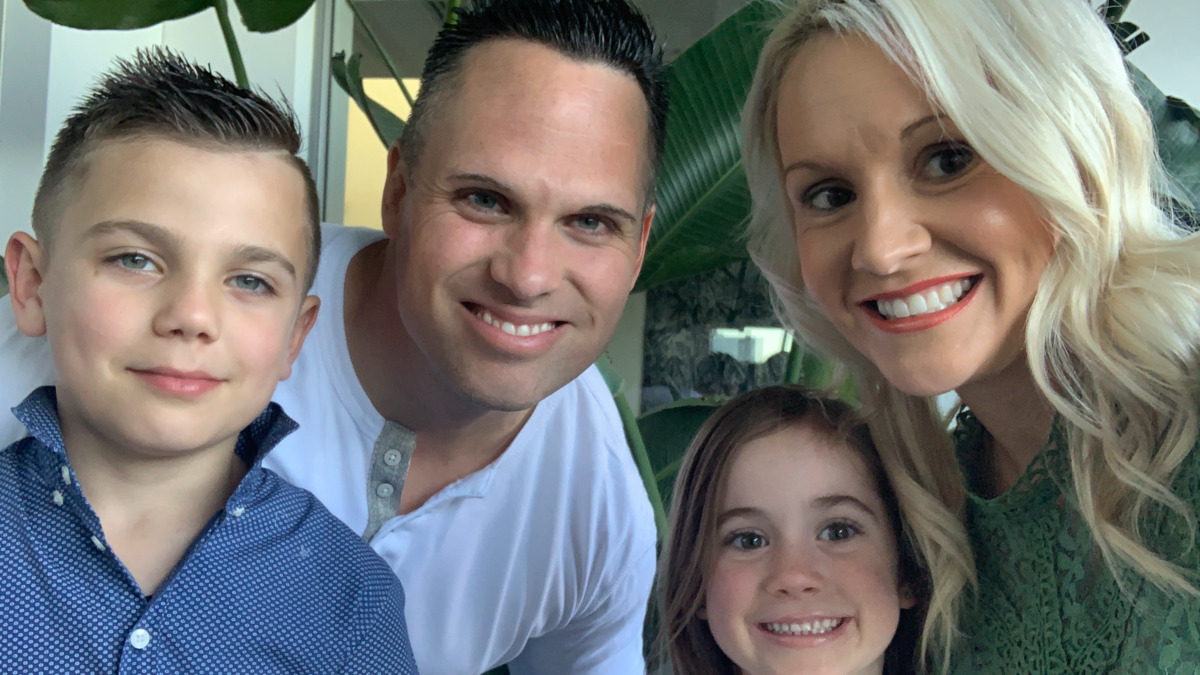 A family of four smile at the camera. 
