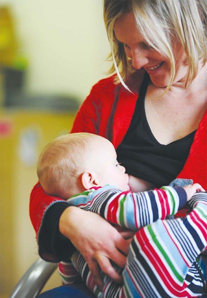 Mother with red sweater breast feeding toddler