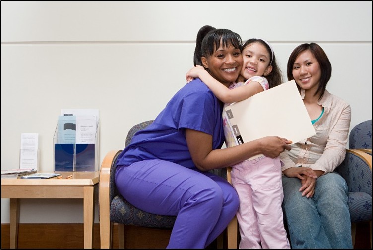 Nurse with purple scrub hugging a girl infront of mother
