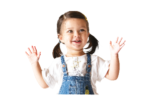 A two year old child is standing and holding her hands up.