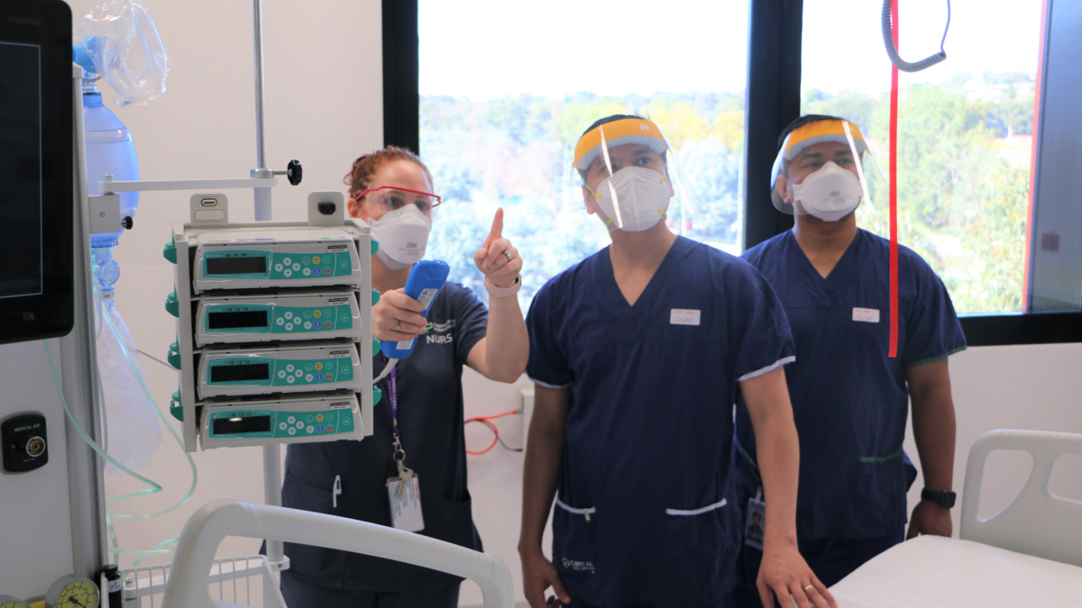 Three nurses are wearing PPE and inspecting the new ICU facilities