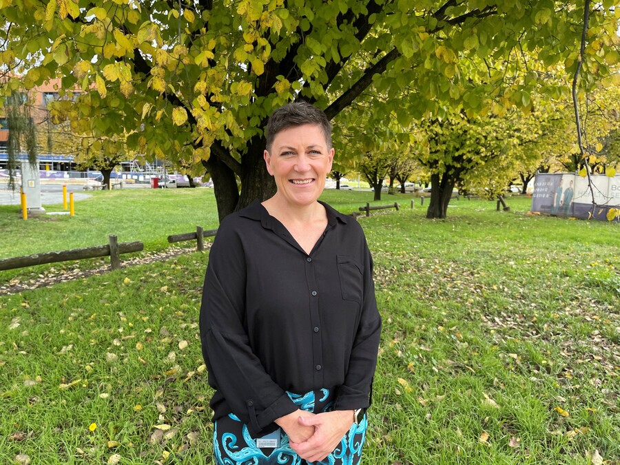 ACT Nurse of the Year Rebekag Ogilvie smiles at the camera. She stands in out the front of Canberra Hospital, in front of a tree. 